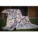 A colorful quilt with star patterns draped over a wooden chair on a grassy area.