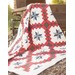 A red chain quilt with gray stars and white background draped over wooden planks.