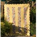 A yellow quilt with colorful patchwork squares displayed on a fence