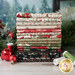 A stack of Christmas fabric in muted shades of red, green, cream, and black surrounded by a holiday garland