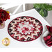 Photo of a floral table topper on a white table with red roses and white plates with red cloth napkins and a houseplant in the background