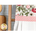 Close up photo of the top of a hanging towel on a small ladder leaning against a wall with a cutting board in the background