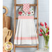 Photo of a hanging towel on a small ladder leaning against a wall with kitchen utensils, a cutting board, and tulips in the background