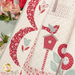 Close up of the draped quilt, showing fabric and stitching details on a block with a bird and birdhouse, as well as the swag borders.