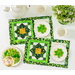 A top down shot of the completed placemats on a white table with white teacups, a white teapot, and plates of shamrock shaped cookies.