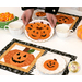 A model holds up a plate of frosted jack-o-lantern cookies in the middle of a staged table with two completed October mats in orange, black, and white.