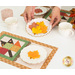 A model sets down a plate of leaf shaped cookies between the two completed mats.