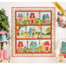 The completed Welcome Home In Spring quilt in bright, cheerful colors, hung on a paneled wall beside pink rainboots, a watering can planter with pink flowers, and a wreath of pink roses. A yellow banner in the upper right hand corner reads "Laser Cut"