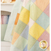 A close up on the draped and completed patchwork receiving blanket in gentle pastel colors.