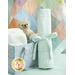 The changing pad, all rolled up and neatly tied, staged beside a diaper bag with a teddy bear. The Patchwork Flannel Receiving Blanket is draped in the background.