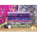 A stack of the fabrics in the Oriental Garden Purple FQ set, with flowers and a fan and thread.