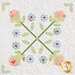 Close up on a block featuring applique details on criss crossing stems with pink and blue flowers.