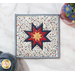 A top down shot of the square hot pad, staged on a white table top with coordinating flowers and a navy blue teapot.