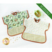 Two of the Toddler Bibs demonstrating the reversible feature, colored in green, cream, and brown fabrics, staged with a green bowl with cereal on a white background.