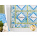 A decorative quilt featuring floral patterns in blue and green, with the words Faithfulness and Gentleness prominently displayed in diamond shapes. A blue pillow is visible to the left, and a logo for Shabby Fabrics is in the bottom right corner.