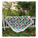 Image of completed quilt draped over a white picket fence 