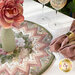 The completed Point of View Folded Star Table Topper in action, holding a vase with a rose in it and staged on a white table with coordinating napkins and wine glasses.