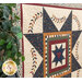 A shot of the quilt from an angle, showing piecing details. A house plant peeks in from the foreground on the left side of the frame.