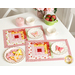 The two completed June placemats, colored in bright pink, red, white, and yellow, staged on a white table with coordinating decor. On white scalloped plates sit beautifully frosted flower and butterfly cookies.