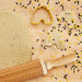 photo of rolling pin with dough showing the honeycomb design with cut out beehive cookies displayed on a wooden table with black and yellow sprinkles