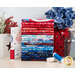 A stack of batik fabrics available in the Liberty 2 collection, with flowers and a candle and jars and thread.