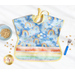 A top down shot of one side of the Toddler bib, showing a light blue fabric with tossed watercolor rainbows and staged with a blue bowl, fork, and cereal.