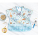 A top down shot of one side of the Toddler bib, showing a light blue fabric with tossed watercolor leaves and portraits of animals and staged with a blue bowl, fork, and cereal.