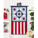 The completed Patriotic Dreams Door Banner, hung on a white paneled wall and staged with coordinating foliage, decor, and furniture.