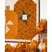 A shot of the wall hanging from a slightly low angle, showing detail on the patchwork pumpkins and fabrics. Coordinating decor peeks into frame.