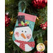 The completed snowman stocking, hung on a green Christmas tree decorated with red bulbs.