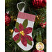 The completed poinsettia stocking, hung on a green Christmas tree decorated with red bulbs.