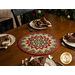 A shot of the completed table topper on a brown table set with four plates set with silverware and coordinating Up On The Housetop napkins in the center of each plate.