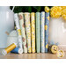 A stack of the fabrics in the Honey Bear FQ set, with a vase and honey jar and thread and a felted bee