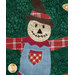 A super close up on the appliqué scarecrow, showcasing his embroidered face.