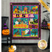 The completed Spooktacular Night Out quilt in cheerful Halloween colors, hung on a paneled wall beside coordinating festive decor like jack-o-lanterns and bats. A yellow banner in the upper right hand corner reads 