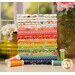 A stack of a colorful fabric bundle with floral patterns, spools of thread, and decorative flowers.