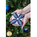 A model holds one of the cathedral ornaments in dark, light, and icy blue with a decorated Christmas tree in the background.