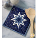 A top down shot of the completed square hot pad in dark blue, staged on a white marbled table with coordinating decor like wooden spoons and Christmas ornaments.