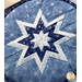 A close up on the folded star center of the hot pad, demonstrating fabric, piecing, and top stitching details.