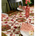 A partial shot of the table runner on a dark wood table, staged with coordinating cloth napkins, table settings, and decor.