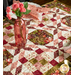 A close up on the table runner, staged with a coordinating table setting and a pink vase with pink flowers.