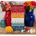 A stack of the fabrics included in the Americana FQ set, with flowers and vases and jars and thread.