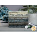 A stack of the fabric included in the Dark & Stormy FQ set, staged with a plant, flowers, and coordinating thread.