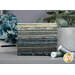 A stack of the fabric included in the Dark & Stormy FQ set, with a plant, flowers, and thread.