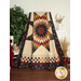 A colorful star-patterned quilt in earthy colors draped over a chair, surrounded by plants and decorative items.