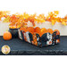 The completed scalloped basket, facing the opposite direction to show other fabrics used, staged on a table decorated for Halloween.