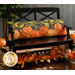 The completed Pumpkin Patch Pillow in flannel and cotton fabric, staged on a black bench surrounded by autumn leaves and decorations.