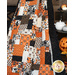 A close up of the finished Witching Hour quilt artfully displayed over a wooden ladder to show dimension and movement. A ceramic pumpkin and coordinating decor sits on the right side of the shot.