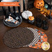 A shot of the backing fabric of the four placemats, slightly fanned out on a brown table and surrounded by coordinating Halloween decor.