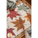 A shot of the maple leaf runner from a slight angle, staged with two table settings with coordinating napkins.